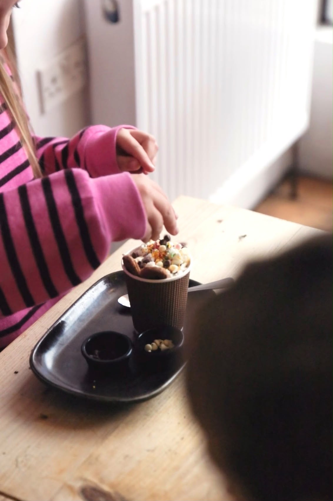 A child adding toppings to a hot chocolate