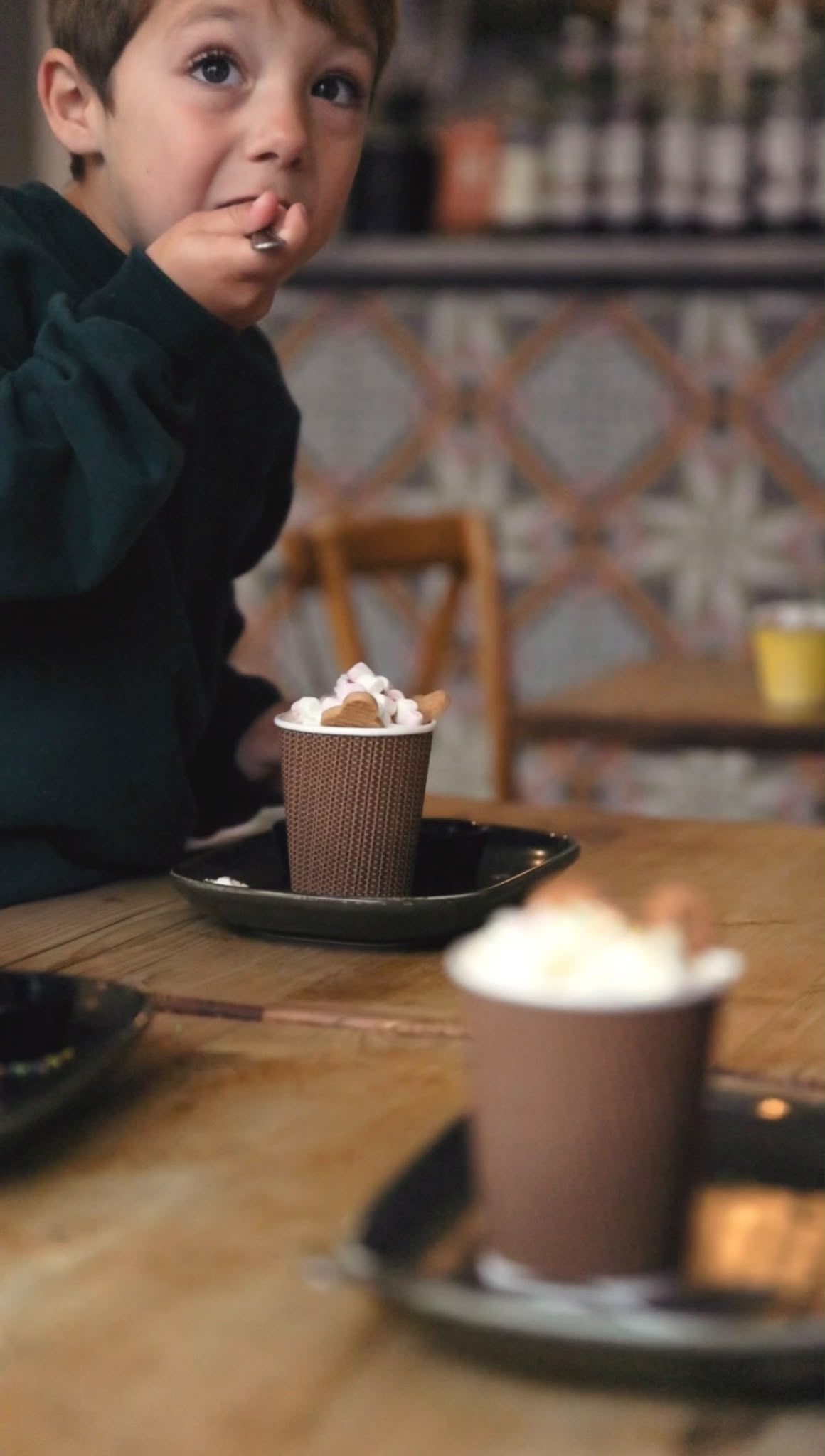A child enjoying a hot chocolate topped with marshmallows